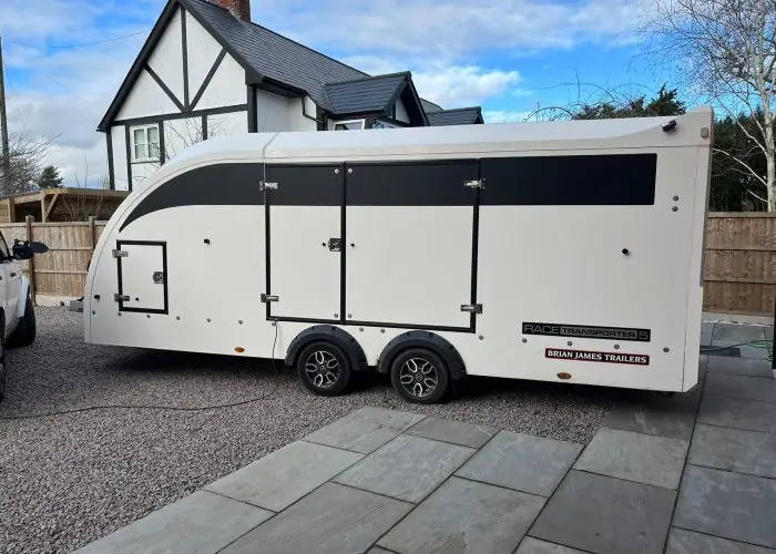 White enclosed car transport trailer parked outside a house