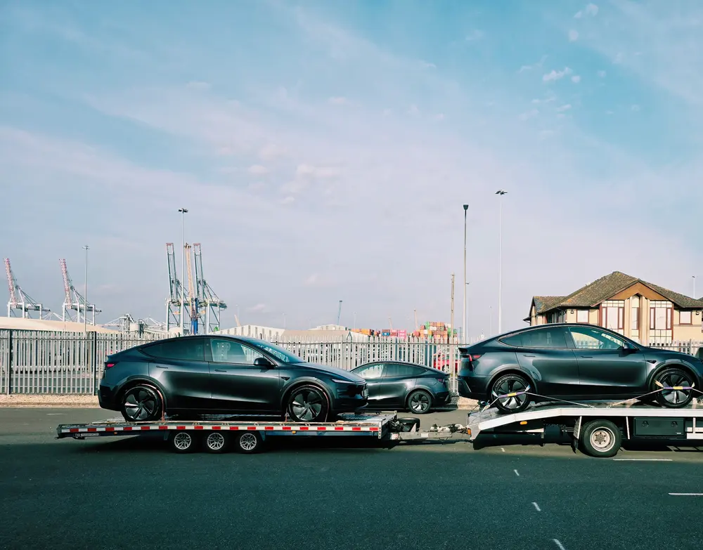 Electric cars secured on a transporter and trailer