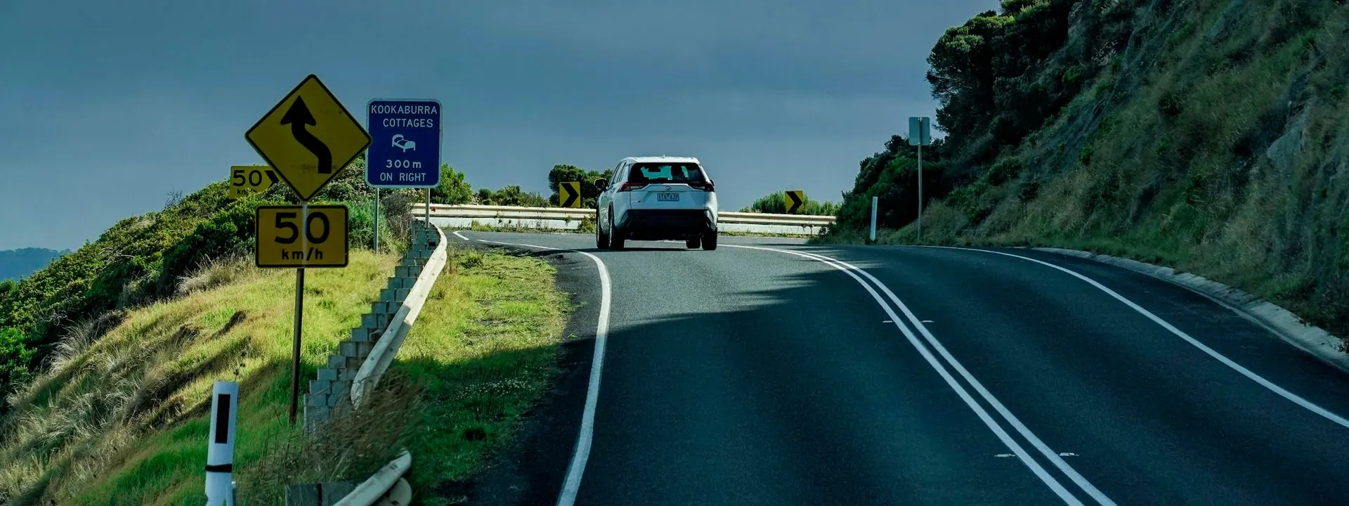 A car travelling along a winding road through green hills