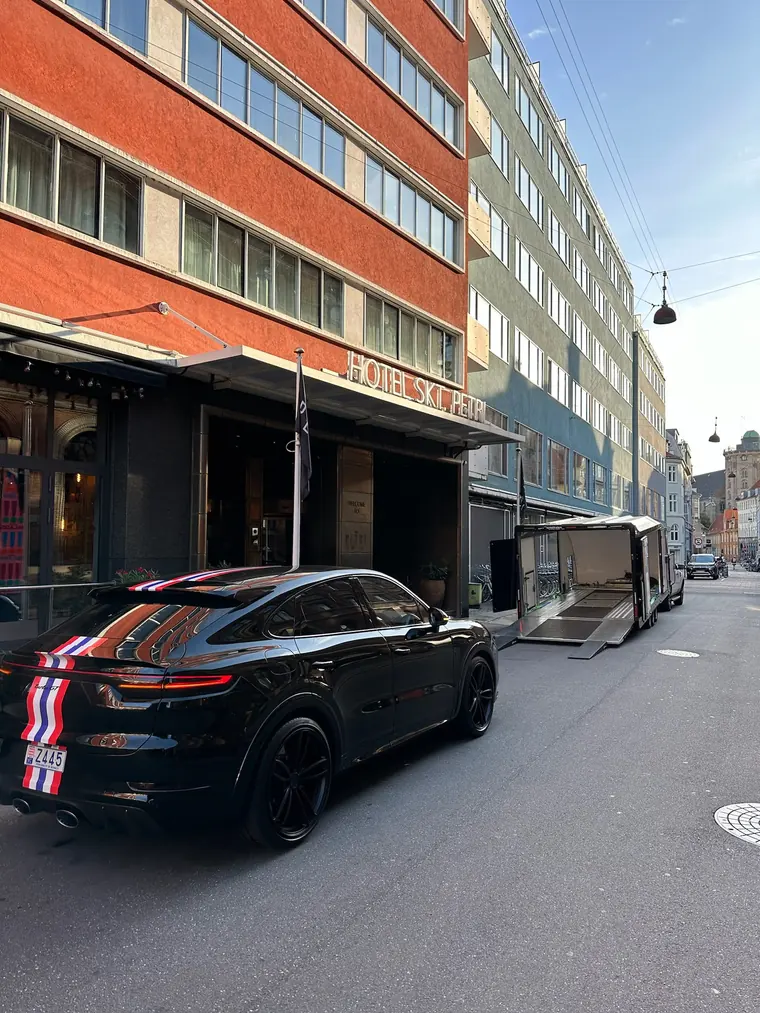 Car collection beside an enclosed trailer in a European city
