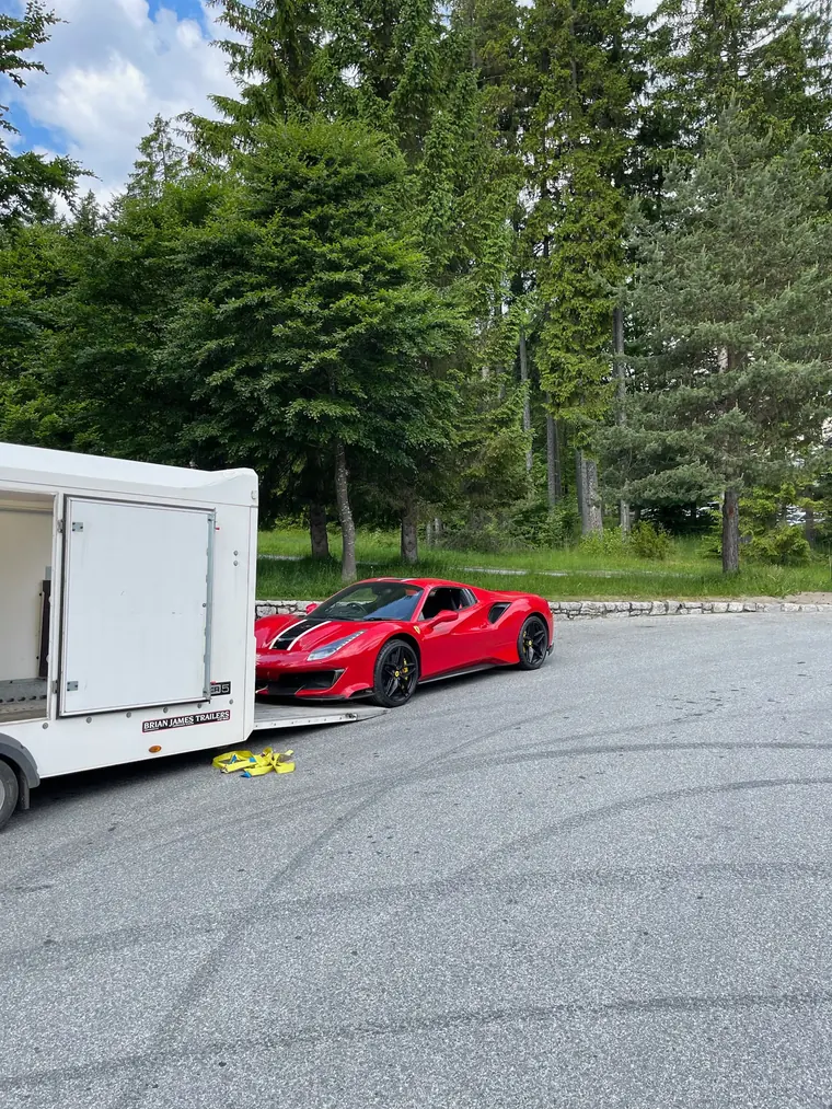 Red sports car being loaded into an enclosed trailer